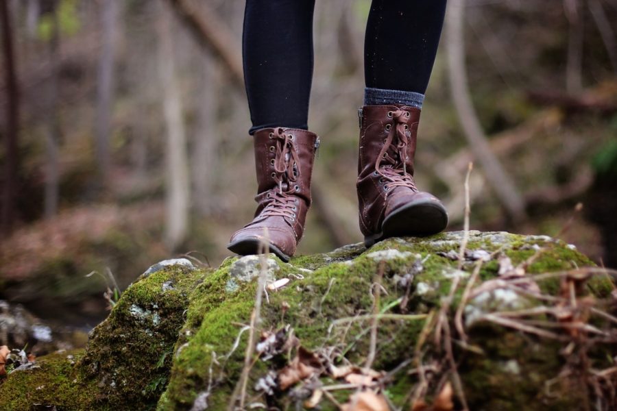 Frau in Wanderschuhen steht auf einem mit Moos bewachsenen Felsen