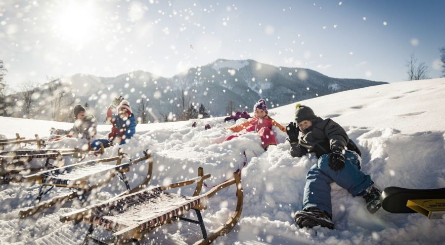 Kinder spielen mit Rodeln im Schnee